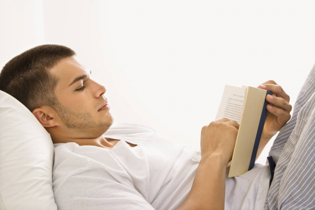Man reading, pillow under shoulders aligns head neck and upper spine
