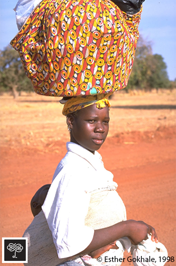 Young woman head loading bundle, Burkina Faso, baby on back, side view