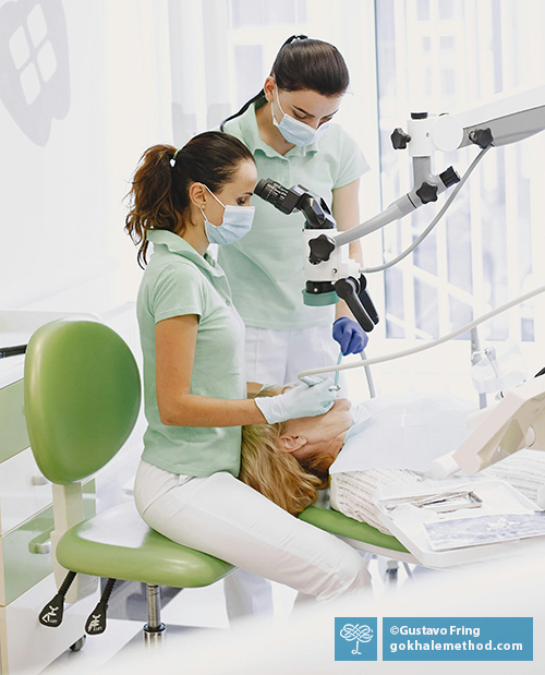 Dentist treating a patient, sitting upright with a relaxed J-spine.