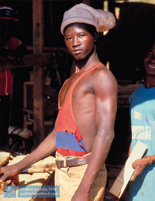African carpenter standing tall by bench 