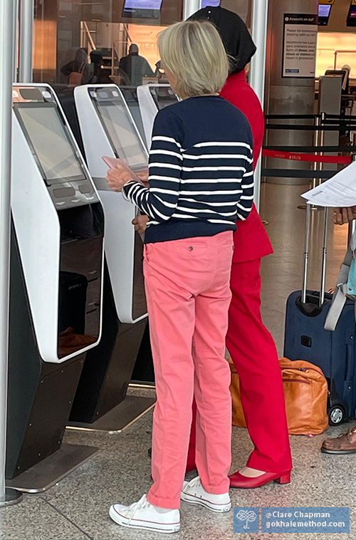 Photo of woman, standing at airport check-in, pelvis tucked and buttocks under-developed.
